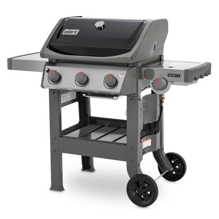 Grill gazowy Weber Spirit II E-320 GBS ustawiony bokiem, z czarną pokrywą i termometrem wskazującym temperaturę, po bokach grilla widoczne są dwie szare półki, z przodu cztery pokrętła z czerwonym wskaźnikiem.