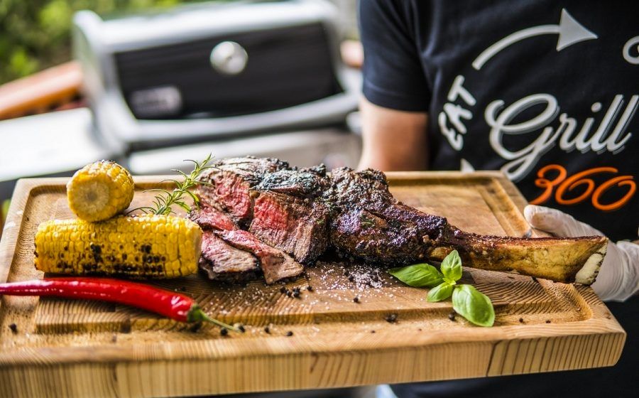 Grillowany stek tomahawk, podany ze słodką kukurydzą na desce.