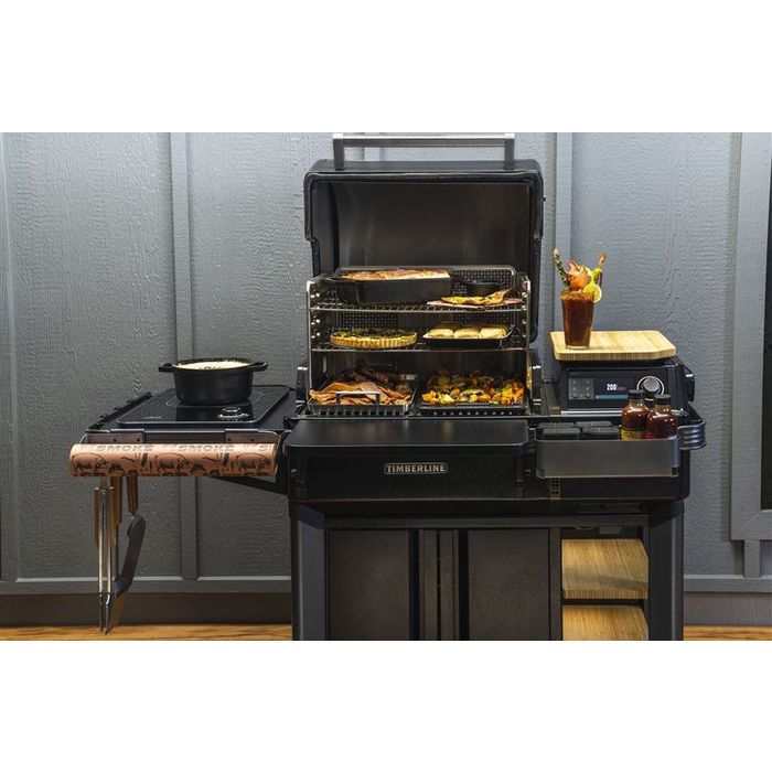 Timberline INT Traeger z włączonym oświetleniem wewnętrznym i potrawami na wszystkich poziomach grillowania.