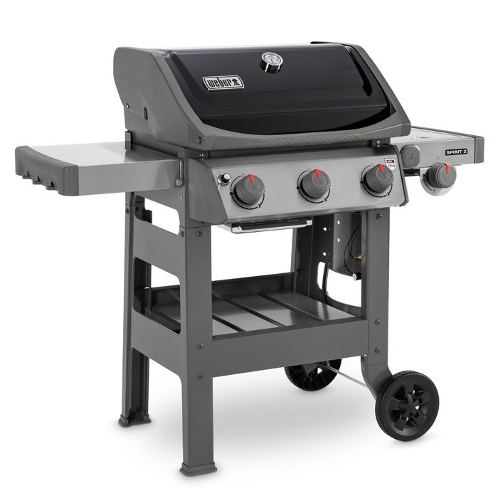 Grill gazowy Weber Spirit II E-320 GBS ustawiony bokiem, z czarną pokrywą i termometrem wskazującym temperaturę, po bokach grilla widoczne są dwie szare półki, z przodu cztery pokrętła z czerwonym wskaźnikiem.