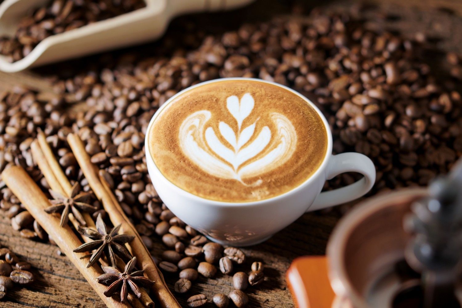 Cappuccino w filiżance i ziarna kawy w tle