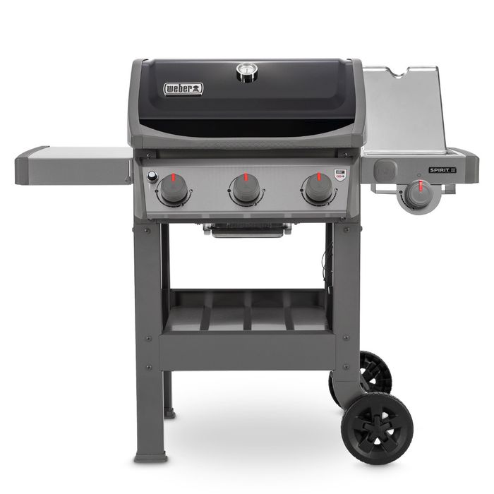 Grill gazowy Weber Spirit II E-320 GBS z czarną pokrywą i termometrem wskazującym temperaturę, po bokach grilla widoczne są dwie szare półki, z przodu cztery pokrętła z czerwonym wskaźnikiem.