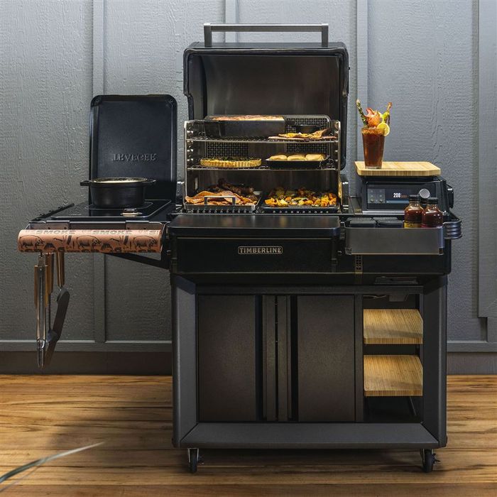 Grill na pellet Timberline INT Traeger ustawiony na tarasie z otwartą pokrywą i boczną płytą indukcyjną.