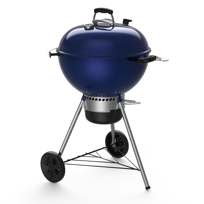 Grill węglowy Weber Master-Touch GBS model C-5750 w pięknym, intensywnym, granatowym kolorze. Grill jest ustawiony tyłem, ma kulisty kształt. Ruszt przykryty granatową pokrywą z chromowanymi elementami, na dole czarny zbiornik na węgiel i dwa, plastikowe 